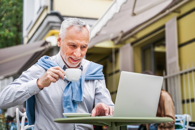 Mature adult using his laptop in a bar coffeehouse