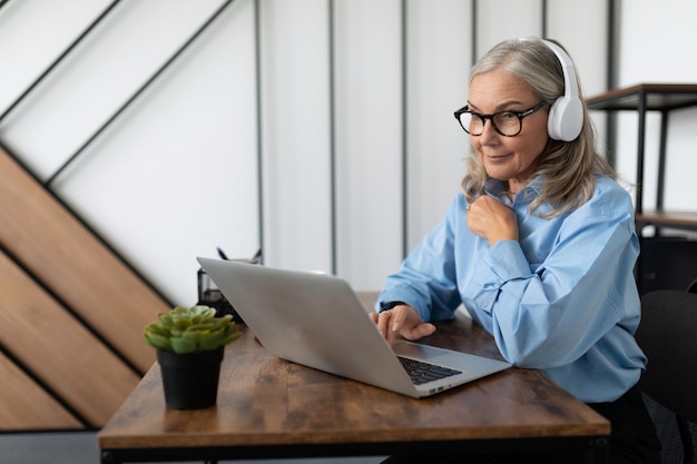 Photo mature adult woman economist with gray hair in a shirt holding a meeting online using the internet