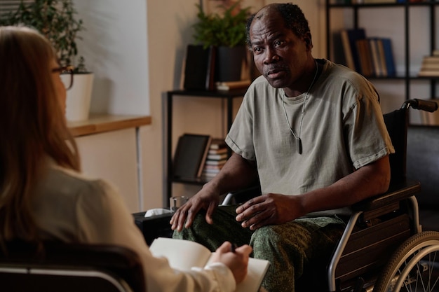 Mature African American Soldier in Wheelchair Listening to Psychologist