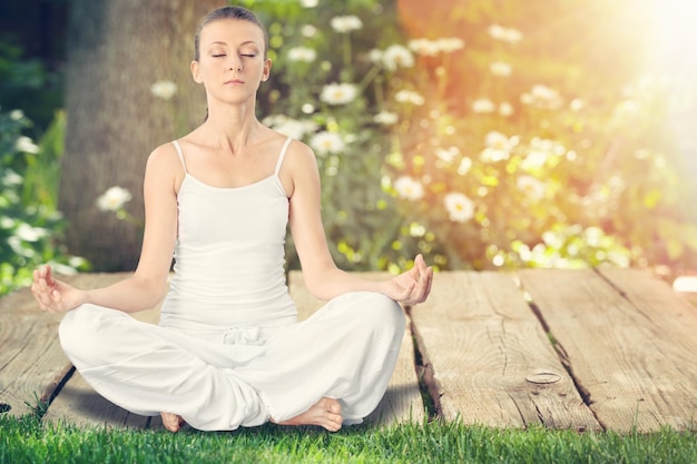 Mature african woman practicing yoga and meditates near swimming pool outdoor.