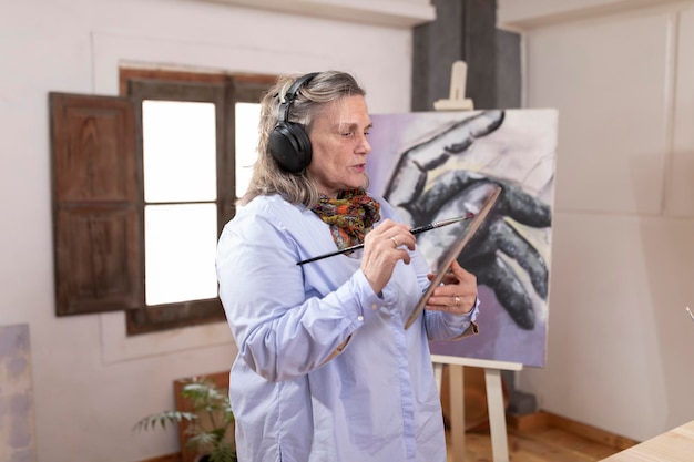 Mature artist woman listens to music while working