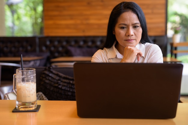 Mature Asian businesswoman relaxing at coffee shop