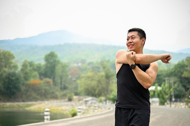Зрелый азиат разогревает свое тело перед тренировкой, растягивая мышцы рук