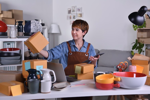 Mature Asian woman entrepreneur, Business owner checking address and delivery detail before shipping product. Online selling business work at home concept