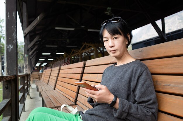 Mature Asian woman sit on a chair and using a smart phone