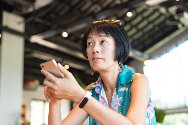 Mature asian woman using smartphone in a coffee shop