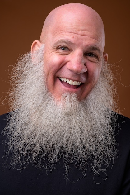 Photo mature bald man with long gray beard on brown