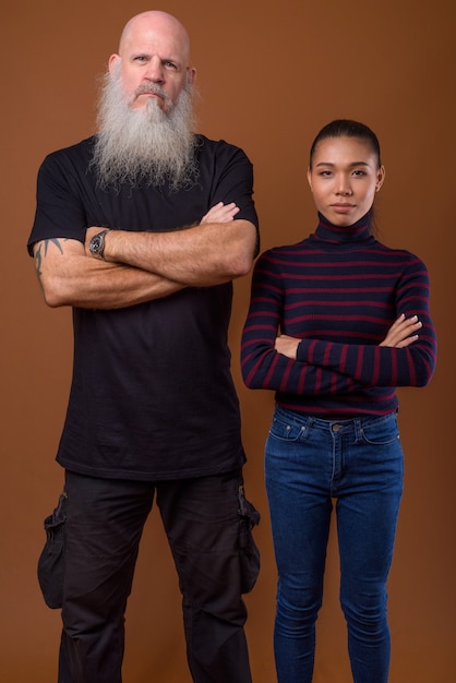 Mature bearded bald man with young Asian transgender woman