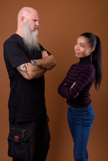 Mature bearded bald man with young Asian transgender woman