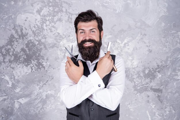 Зрелый бородатый мужчина в парикмахерской с профессиональной винтажной бритвой и прической ножниц