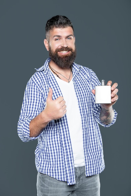 Mature bearded man hold male perfume bottle thumb up