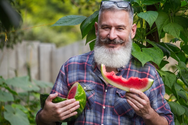 Mature bearded man with a watermelon slice