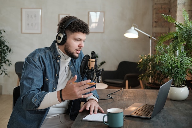 Mature bearded radio dj in headphones broadcasting at the table working on radio