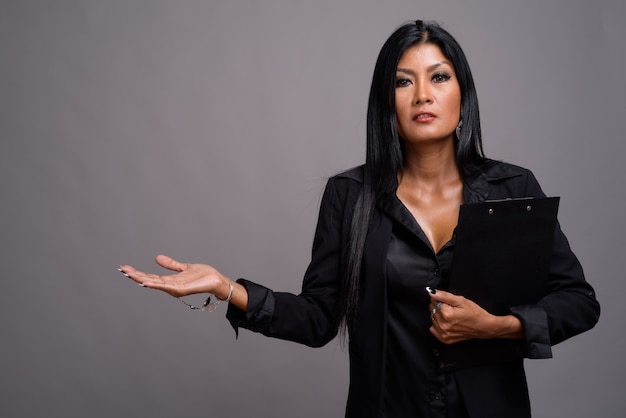 Mature beautiful Asian businesswoman against gray background