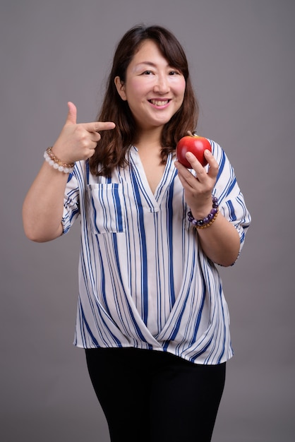 mature beautiful Asian businesswoman holding apple