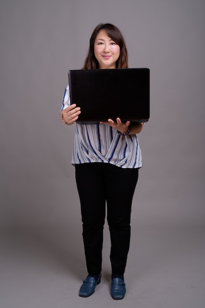mature beautiful Asian businesswoman holding laptop
