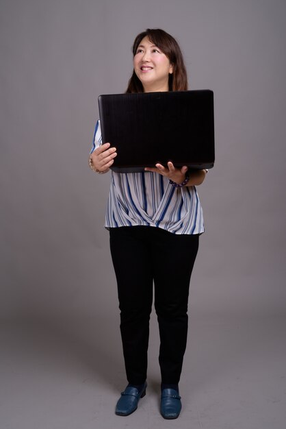 mature beautiful Asian businesswoman holding laptop