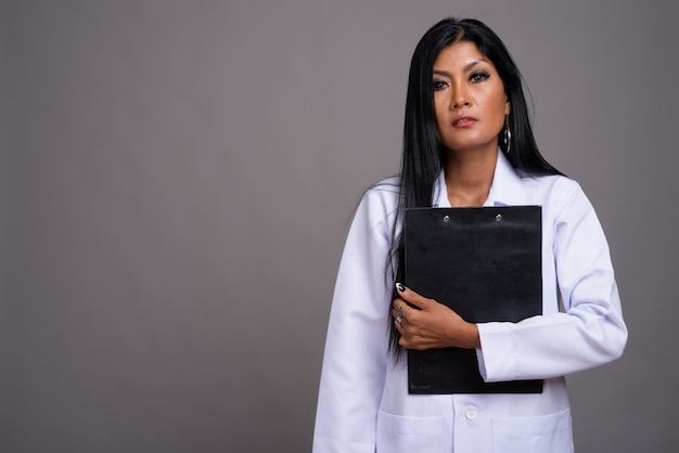 회색 배경 성숙한 아름다운 아시아 여자 의사