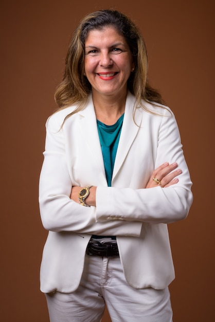 Mature beautiful businesswoman on brown wall