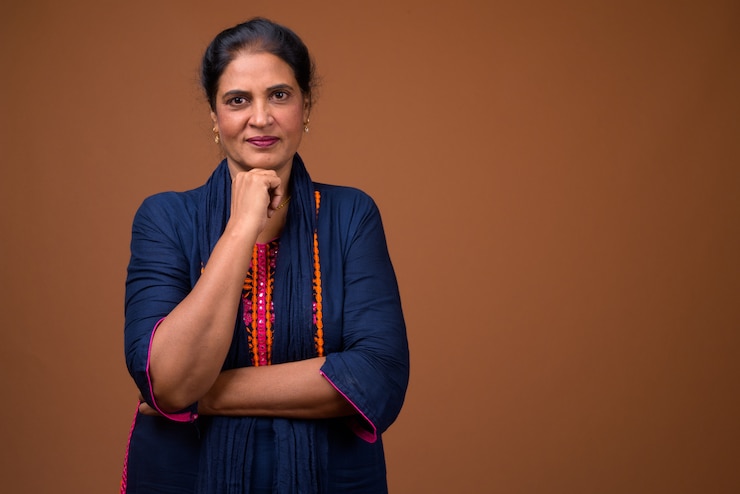 Photo mature beautiful indian woman against brown wall