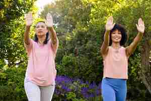 Photo mature biracial woman and young biracial woman practicing yoga outdoors at home