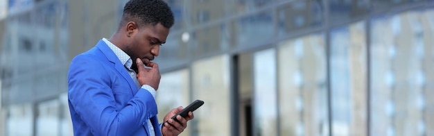 L'uomo di colore maturo guarda il telefono con un'espressione premurosa