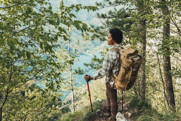 Mature black woman standing on the top a hill and enjoying the view during her hike in the mountains.