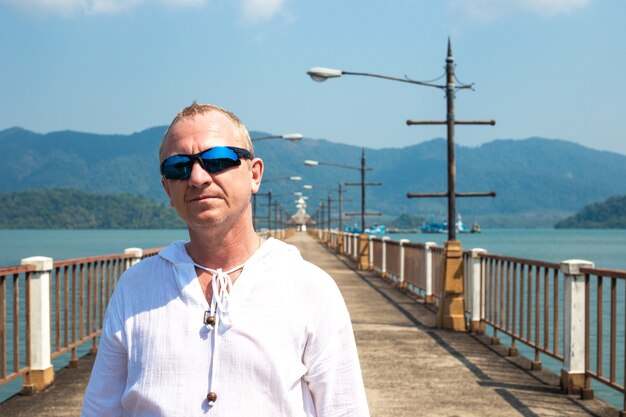 Mature blond man on a pier at sea in asia