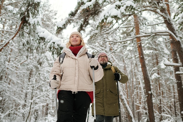 Mature blond woman in winterwear walking in front of her husband