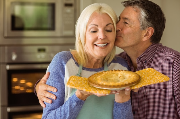 Mature blonde holding fresh pie with husband kissing her