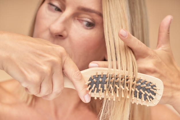Mature blonde woman combing her hair selective focus