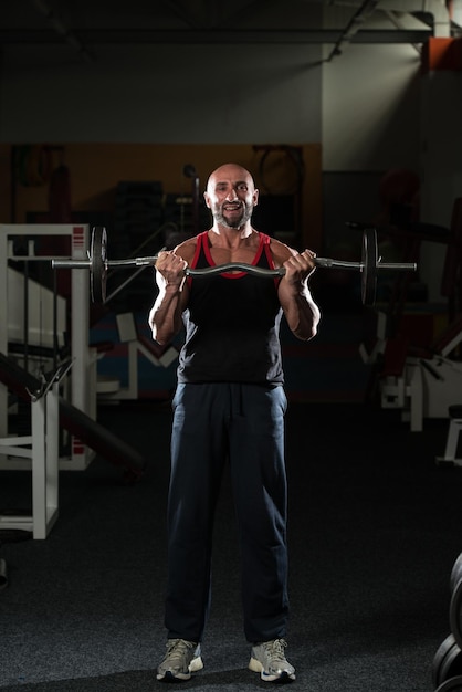 Mature Bodybuilder Exercising Biceps With Barbell