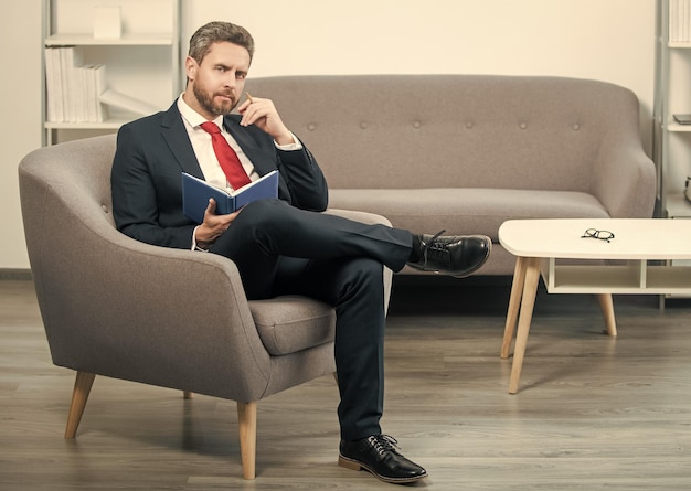 Mature boss in suit sit in office making notes in notebook