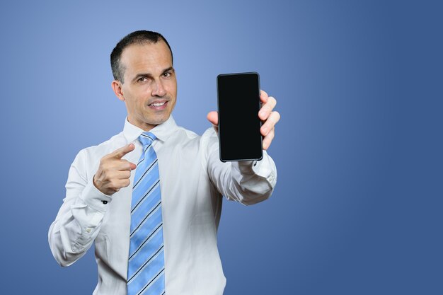 Mature Brazilian man in formal wear showing his smartphone and pointing his finger at him