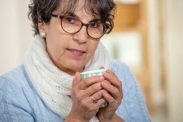 Mature brunette woman with glasses drinking cup of tea