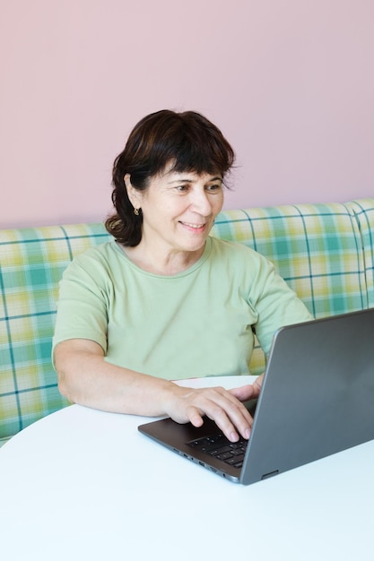 Mature brunette woman works in front of a laptop in a cafe