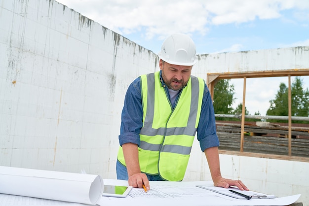 Mature Builder Looking at Floor Plans on Site