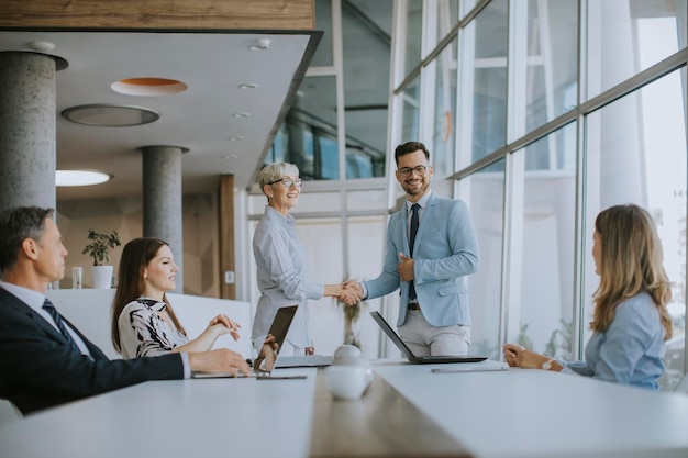 Mature business woman handshaking with young colleague on a meeting in the office