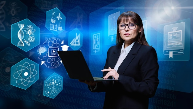 Photo mature business woman headmaster of college school with laptop serious confident female teacher mentor manager businesswoman in black suit looking at camera digital background with education icons