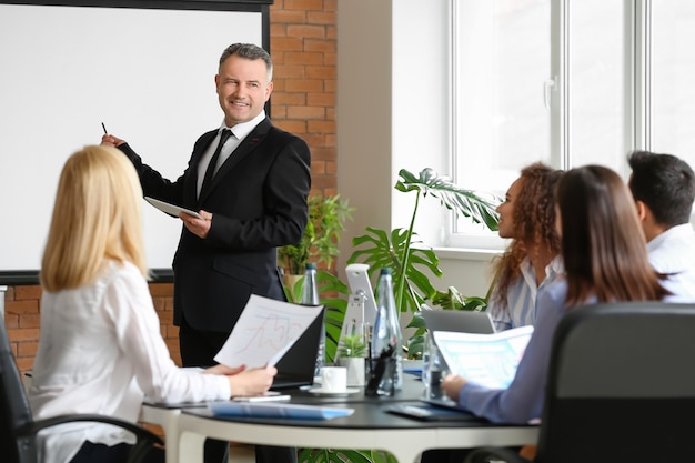 Mature businessman giving presentation during meeting in office