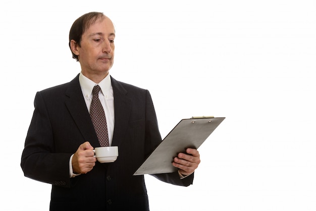 mature businessman holding coffee cup while reading