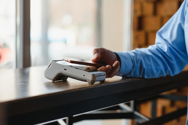 Photo mature businessman paying with contactless credit card with nfc technology