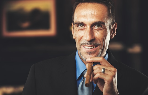 Photo mature businessman smoking a cigar in a classy room