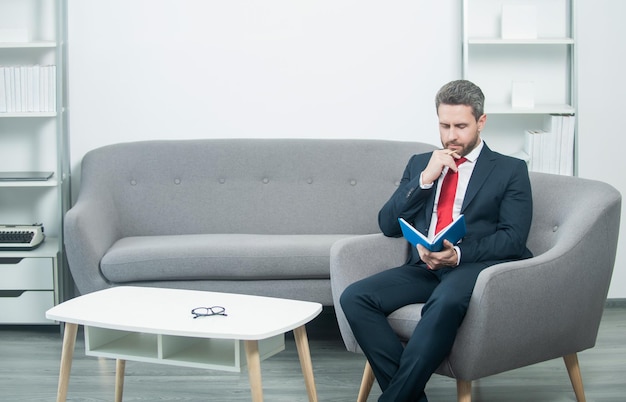 Mature businessman in suit sit in office with planner