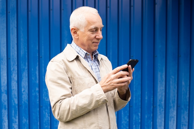 Зрелый бизнесмен с помощью смартфона в синем