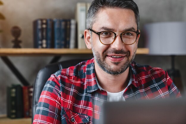 Mature businessman wearing eyeglasses while using laptop in home office