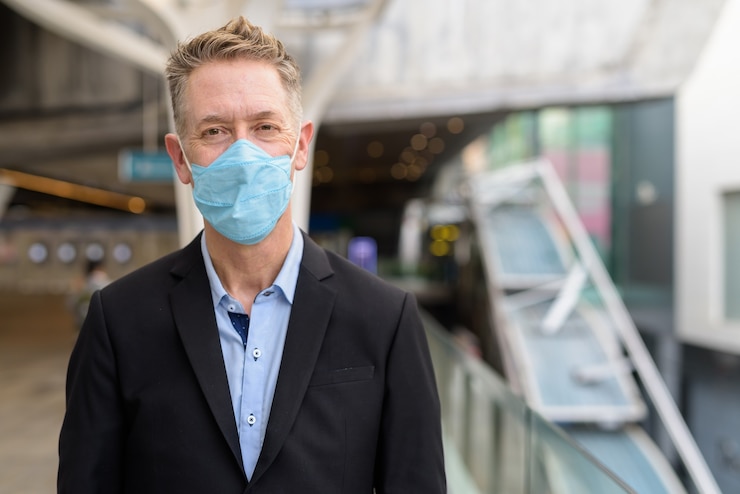 Photo mature businessman wearing mask for protection from coronavirus outbreak at the footbridge