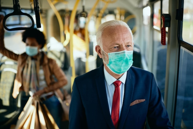 Mature businessman wearing protective face mask while commuting by public transport