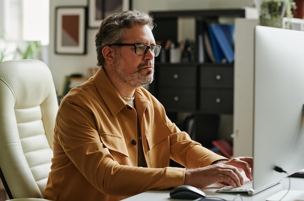 Mature businessman with grey hair and beard typing on keyboard