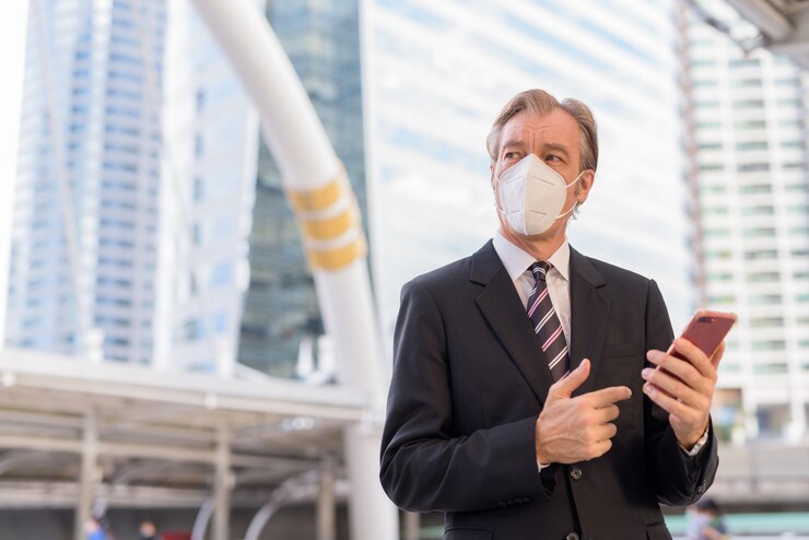 Photo mature businessman with mask thinking while using phone at skywalk bridge